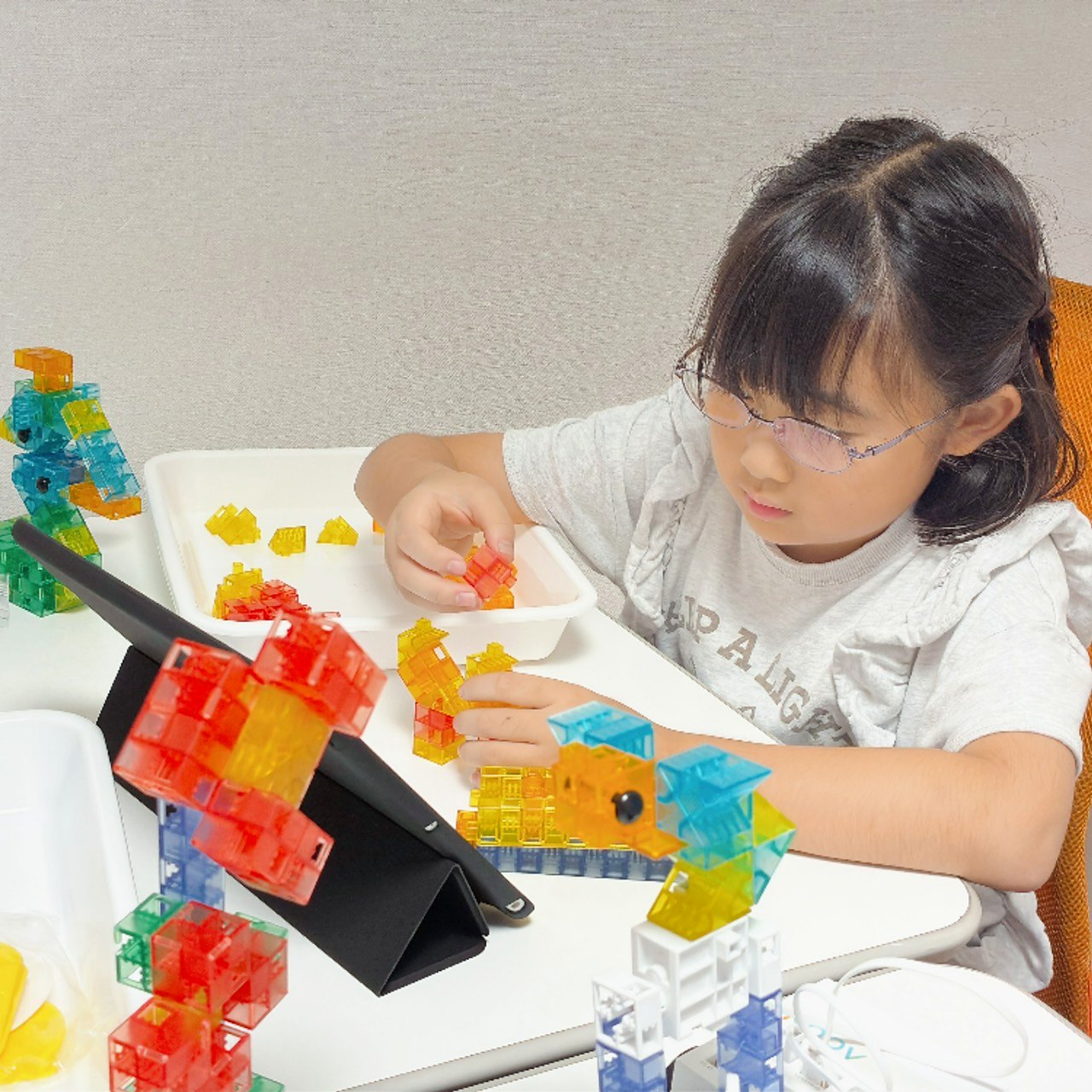カラフルな半透明のKOOVのブロックを組み立てる子ども