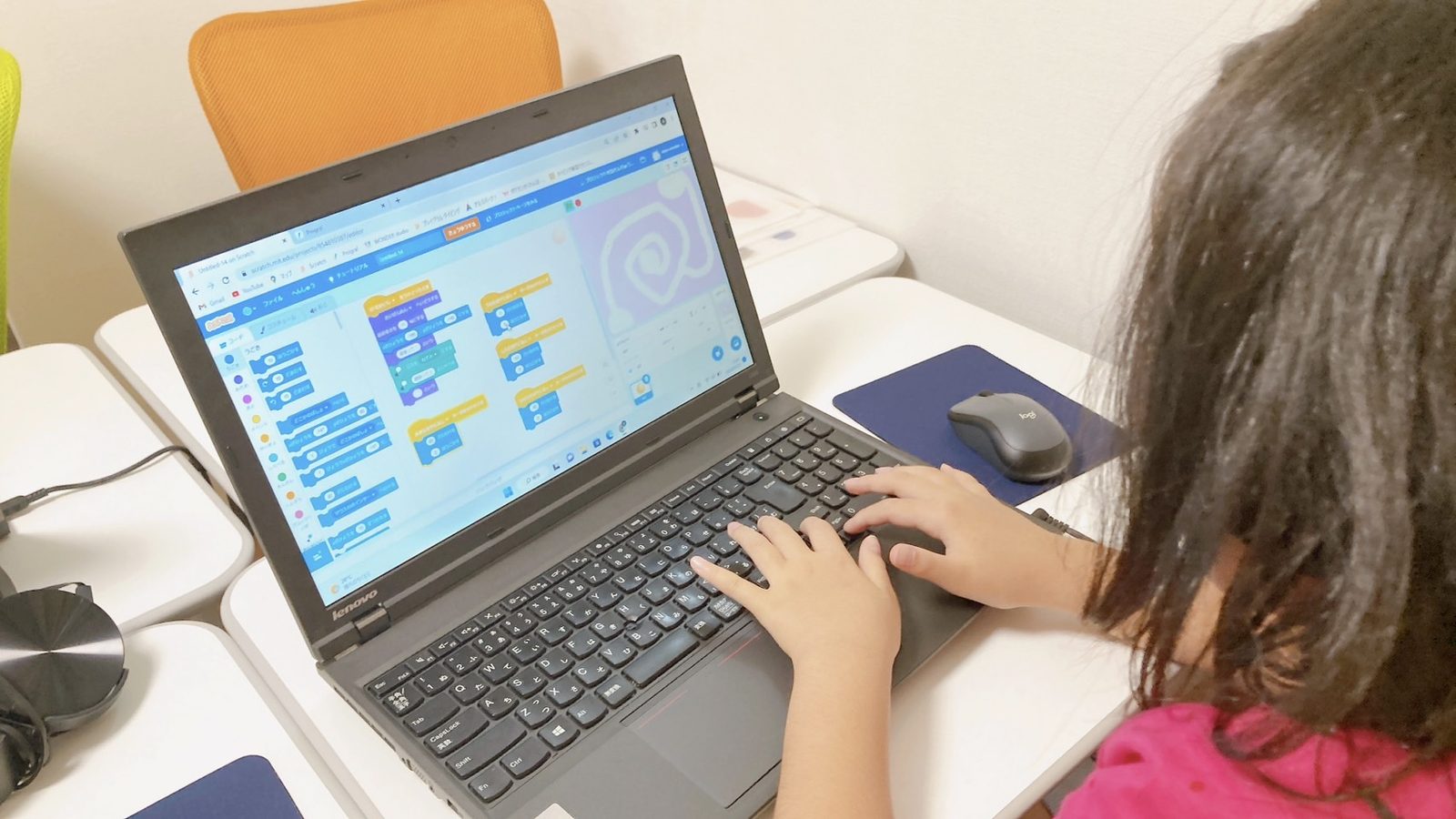 パソコンの画面でScratchのブロックを組み合わせ、キーボードで入力する子どもの手元